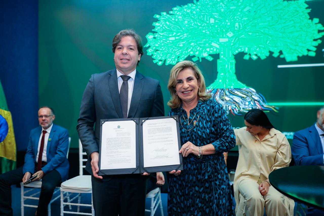 Fotografia com a presença de um homem e uma mulher, ambos segurando um termo de cooperação.