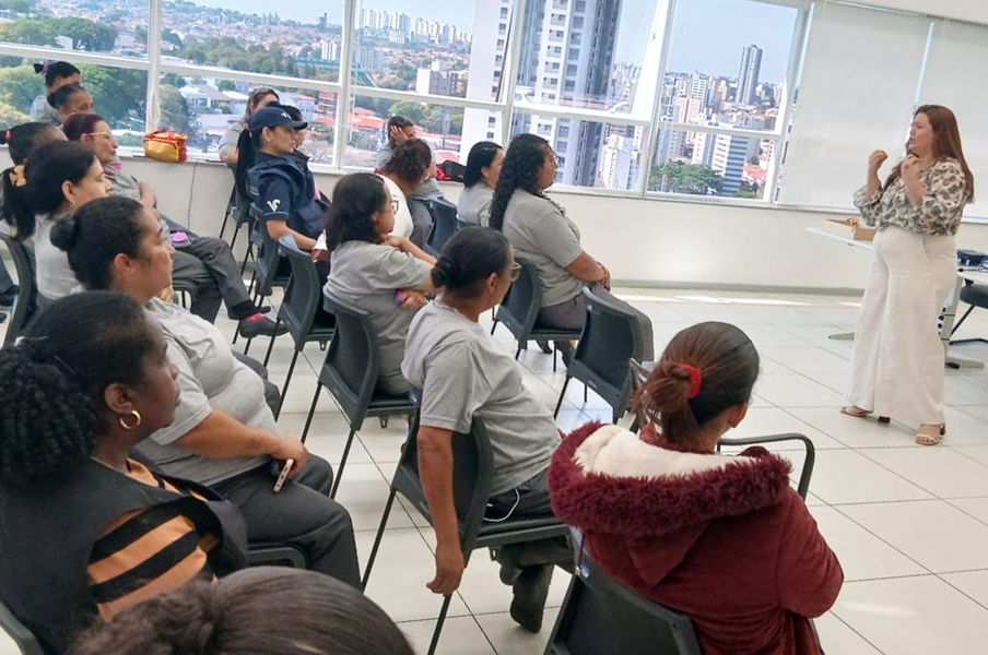 Fórum Trabalhista de Campinas promove roda de conversa com terceirizadas em alusão ao Outubro Rosa - CSJT2 9 Fotografia com mulheres sentadas em diversas cadeiras e uma mulher em pé falando algo.