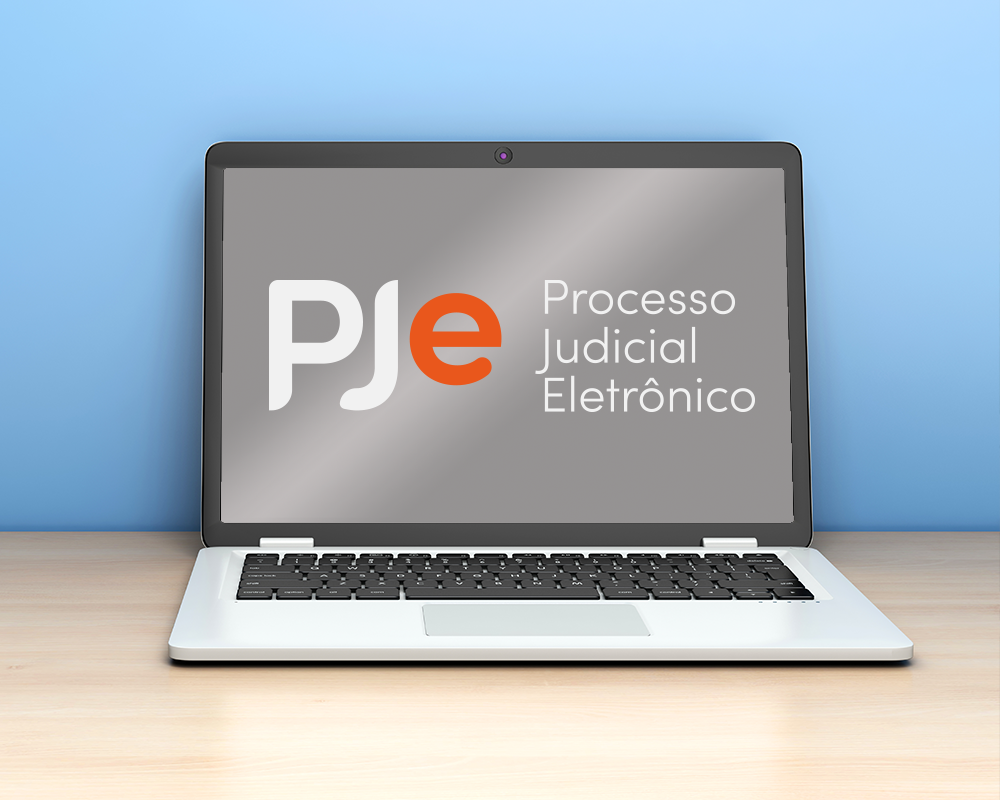 Imagem ilustrativa de notebook em uma mesa com a logo do PJe na tela.