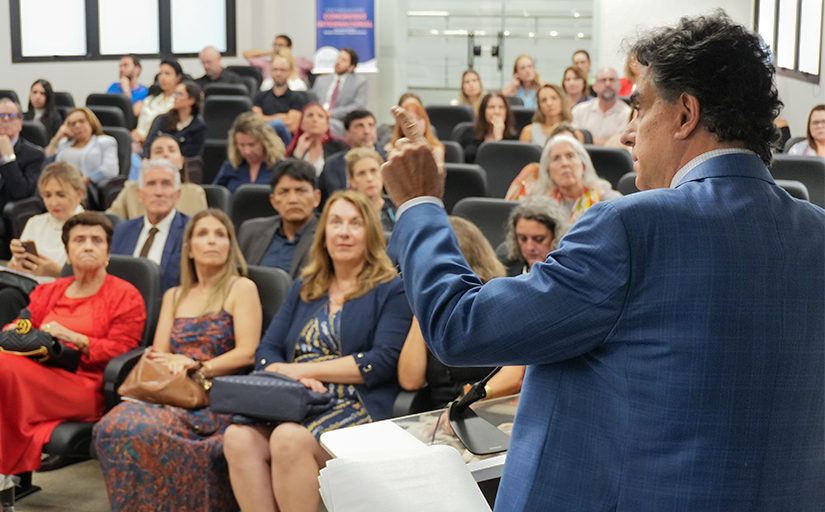 Presidente do TST encerra congresso da Ejud-12 sobre Direitos Humanos e Trabalho Decente - CSJT2 3 Foto de um homem de costas, de terno, dando uma palestra. Ao fundo o público assistindo.