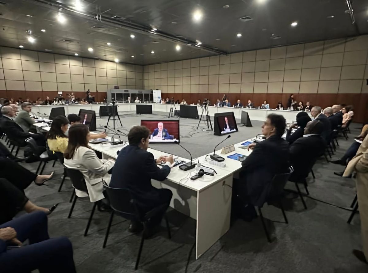 Todas as Notícias 3 Foto do evento. Uma grande mesa quadrada com diversas pessoas sentadas.