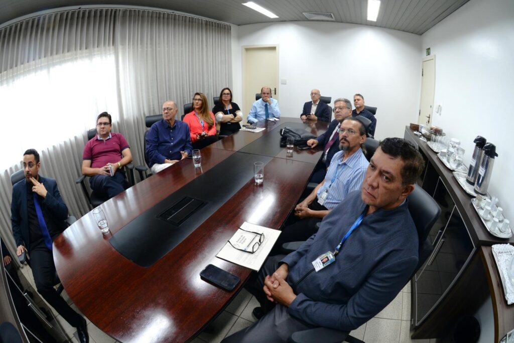 Fotografia com diversas pessoas ao redor de uma mesa, sendo 11 pessoas, 9 homens e 2 mulheres.