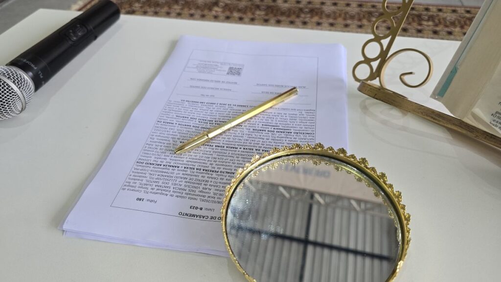 Casamento comunitário encerra itinerância em Araguatins (TO) - CSJT2 3 Mesa da cerimônia de casamento coletivo, com microfone, caneta e bandeja dourada para alianças e certidões de casamento